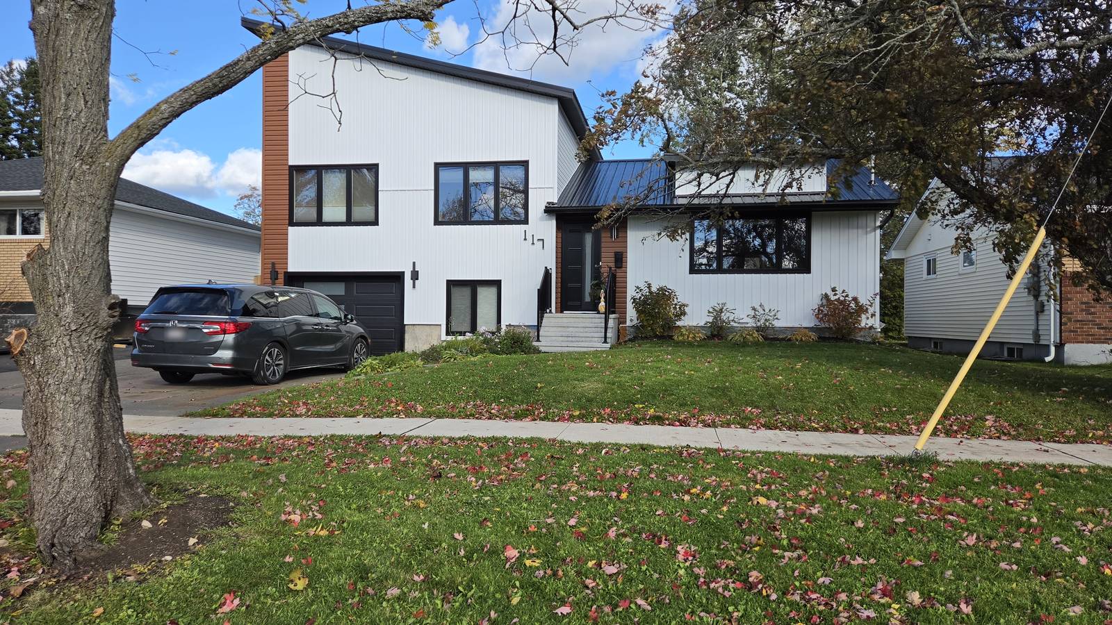 The finished home after the four-room addition and redesign, white siding with a rust accent wall and black trim