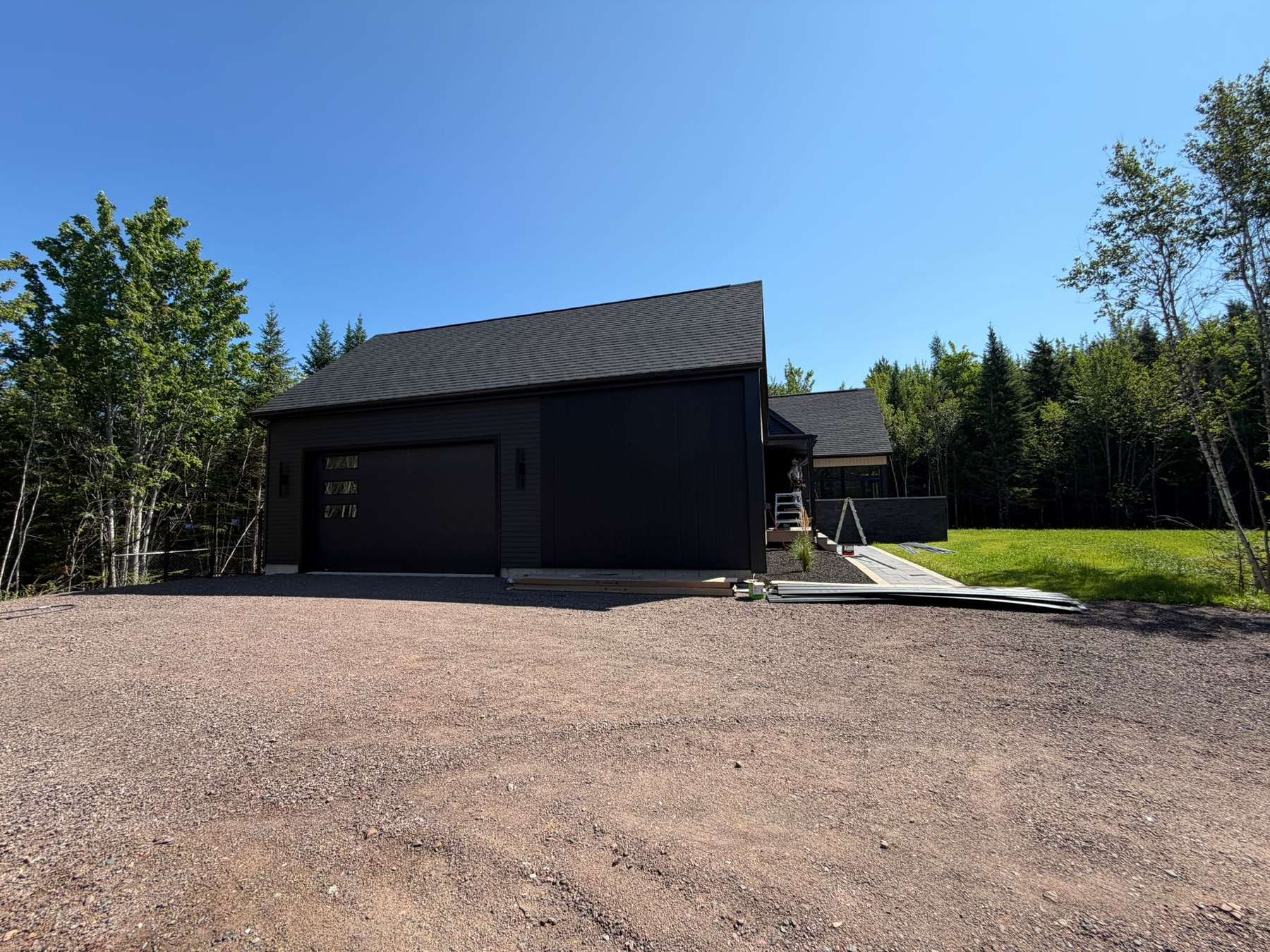 Finished custom home and attached garage at the end of a gravel driveway