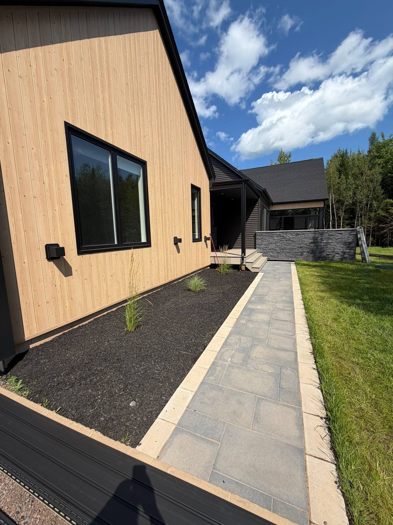 Board-and-batten siding and stone walkway along the side of the finished home