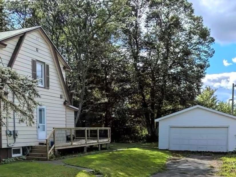 Side of the house before renovation, with a small worn deck and a white detached garage
